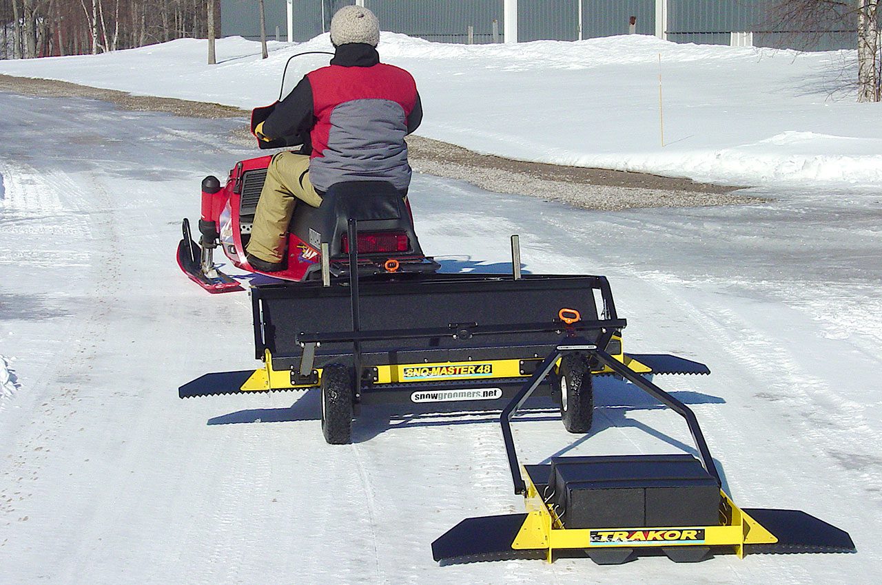 snow groomer towed by snowmobile.
